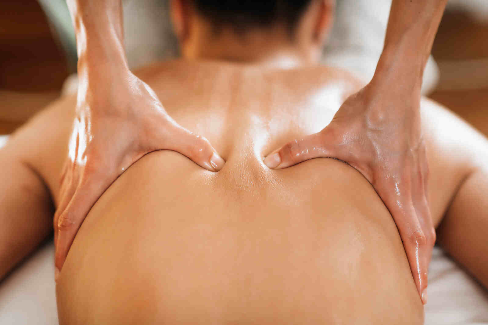 Close-up of a person receiving an Ayurvedic massage for neck pain, featuring expert hands applying herbal oil onto the back, symbolizing holistic healing therapy in Hyderabad.