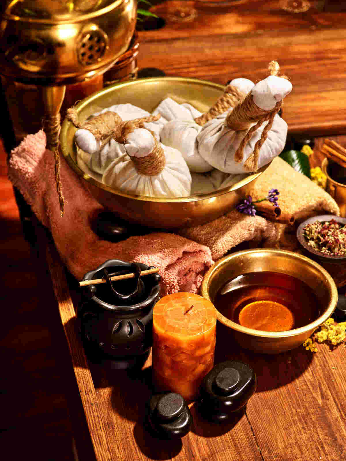Ayurvedic treatment setup in Hyderabad with herbal poultices, essential oils, and a candle on a wooden table, used for neck pain relief through holistic therapies in 2025.