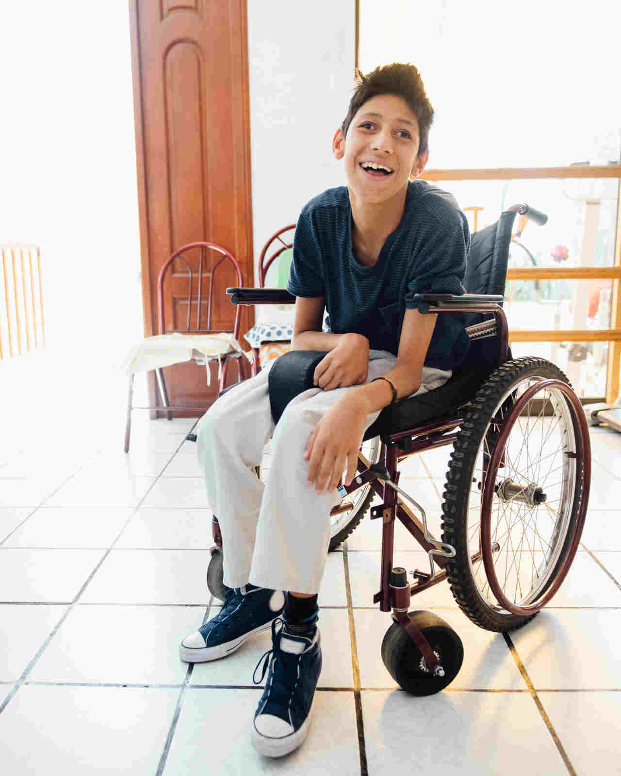 Young boy in a wheelchair smiling indoors, representing patients benefiting from holistic Ayurvedic MS treatment in Hyderabad, aiming to improve quality of life.